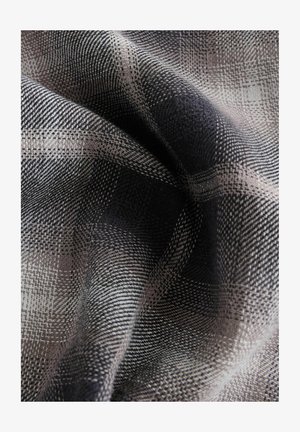 Tkanina so širokým vzorom v šedých a čiernych štvorcoch s jemnou textúrou, ktorá zobrazuje detailné prepojenia a jemné kontrasty.