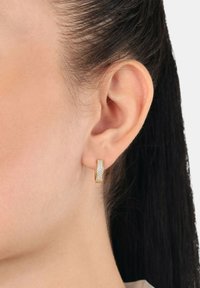 Złota kolczyka w formie obręczy z teksturowaną srebrną powierzchnią i wypolerowanym brzegiem, prezentująca smukły, zakrzywiony kształt i błyszczące wykończenie.