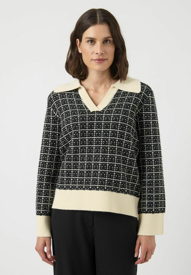 Svart och krämfärgad stickad tröja med V-ringning, kontrasterandekrage, rutigt mönster samt ribbade muddar och fåll. Lös passform.