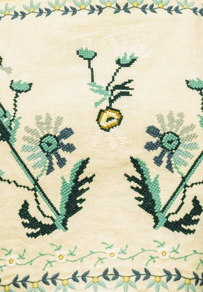 Σχεδίαση με κέντημα σταυροβελονιάς με πράσινους μίσχους, μπλε και λευκά λουλούδια και κίτρινες λεπτομέρειες σε μπεζ ύφασμα με πλαίσιο από μπλε και κίτρινο λουλουδάτο μοτίβο.