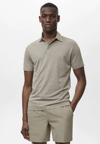 Polo grigio chiaro con maniche corte, colletto piatto e pattina con tre bottoni, abbinato a pantaloni corti beige. Tessuto morbido, design semplice.