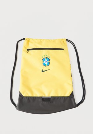 Mochila amarilla y negra con cordón, con el emblema de fútbol de Brasil CBF, pequeño bolsillo delantero con cremallera y logo negro de Nike Swoosh en el frente.