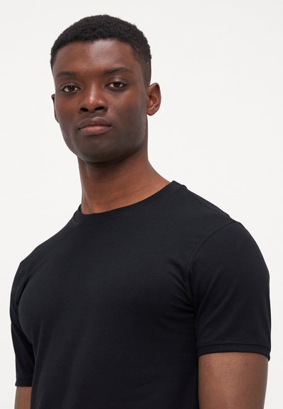 Juodas trumpa rankove T-shirts pagamintas iš lygaus, tamprių audinių su apvaliu iškirpimu ir minimaliais siuvimo detalėmis.