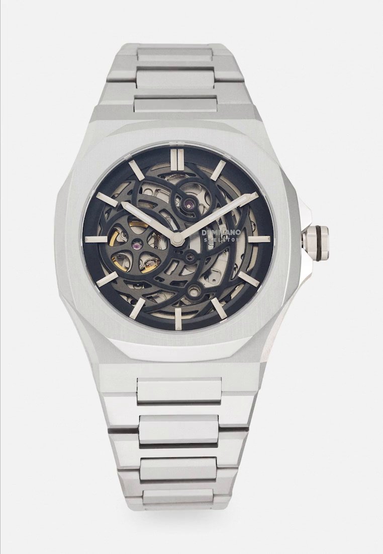Montre-bracelet argentée en acier inoxydable, avec un cadran sombre ajouré, des engrenages mécaniques visibles, des index horaires clairs et un bracelet métallique assorti.