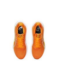 Des chaussures de sport orange vif avec une tige en maille texturée, une semelle intermédiaire blanche et une semelle externe noire. Elles sont dotées de lacets plats et d'accents réfléchissants.