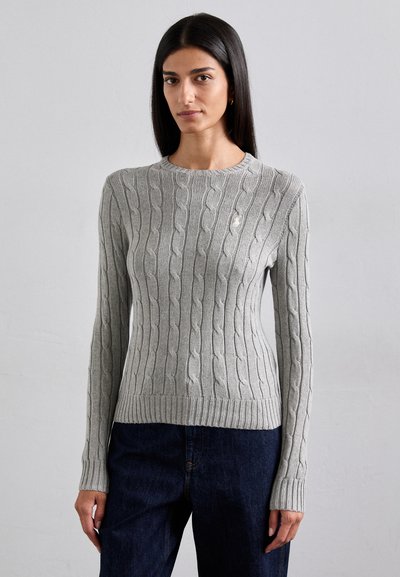 Grå kabelstrik sweater med lange ærmer, rund halsudskæring og ribbet kant. Har et diskret logo på brystet, båret med mørke jeans.