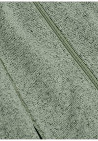 Lichtgroene stoffen tas met rits, voorzien van een zachte, gestructureerde oppervlak. Zichtbare stiksels langs de randen en een goed gedefinieerd ritsloop.