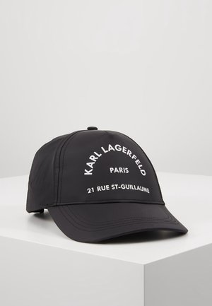 Zwarte baseballpet met gebogen witte tekst waarop staat "KARL LAGERFELD PARIS 21 RUE ST-GUILLAUME", weergegeven op een witte ondergrond.