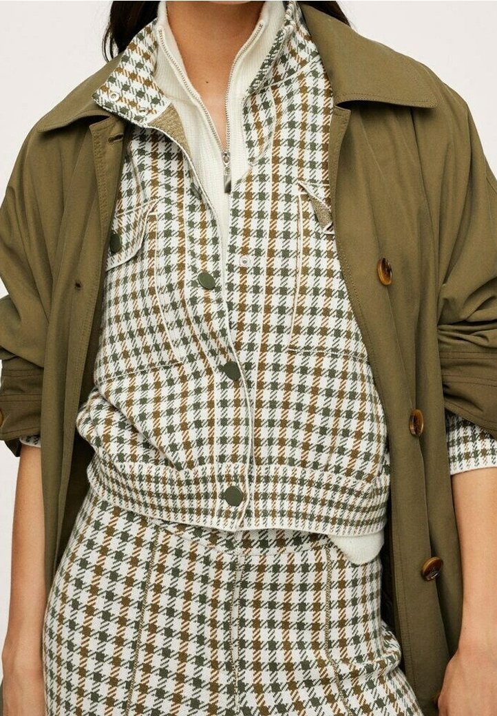 Wieloczęściowy zestaw z oliwkową zieloną kurtką, nałożoną na bluzkę w kratę w białym, brązowym i zielonym kolorze. Teksturowany materiał z guzikami.