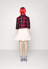 Svart och röd rutigt kort jacka med trekvartslånga ärmar, i kombination med en knälång rosa volangkjol och lavendelfärgade klackar.