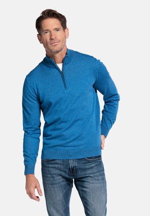 Blauwe pullover met ritssluiting in zachte gebreide stof, met lange mouwen en geribde manchetten. Gecombineerd met blauwe spijkerbroek.