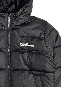 Giacca a vento nera con zip anteriore, dotata di cappuccio, design trapuntato e logo bianco "Disclaimer" sul petto. Texture liscia.