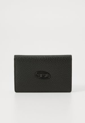 Black textured leather cardholder with a smooth oval logo accent on the front. Compact rectangular shape, clean lines, and minimalistic design.