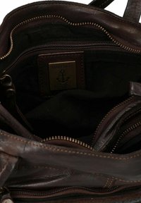 Sac à main en cuir marron avec un intérieur spacieux, doté d'une doublure en tissu sombre, de plusieurs poches zippées et d'une étiquette de marque en métal.