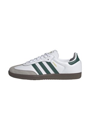 Hvid Adidas Samba sneaker med grønne striber, grå ruskindsspids, brun sål og hvide snørebånd set fra siden.