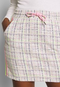 Shorts en tweed dans une palette de couleurs pastel avec un motif à carreaux. Équipés d'une taille à cordon de serrage et de poches latérales avec des accents néon.