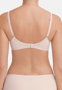 Reggiseno beige chiaro con spalline regolabili, finitura liscia e delicati bordi a scallop. Chiusura sul retro con tre ganci per una vestibilità sicura.
