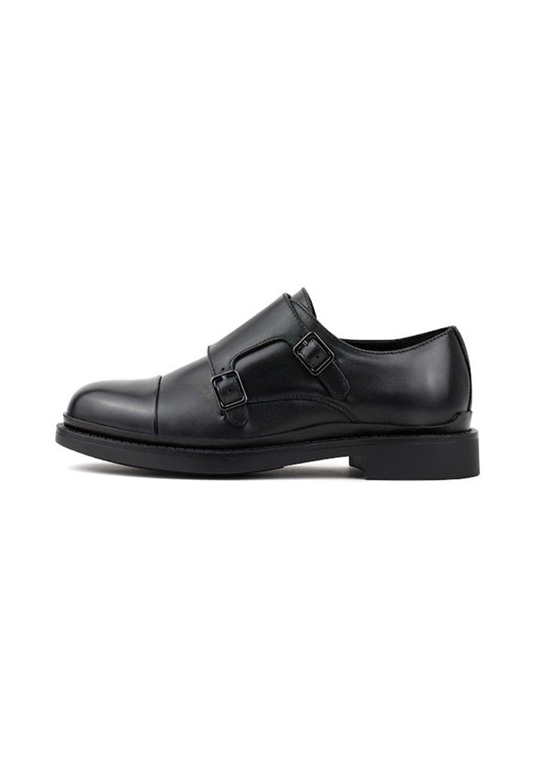 Czarne skórzane buty typu monk strap z podwójnymi klamrami, gładką teksturą, okrągłym czubkiem i lekko podniesioną czarną gumową podeszwą.