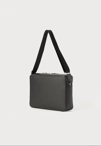 Borsa rettangolare nera realizzata in materiale testurizzato, con una tracolla removibile e una chiusura con zip nella parte superiore.