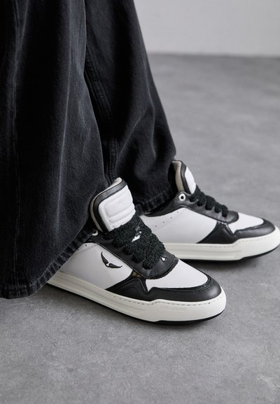 Sneaker alte in bianco e nero con dettaglio in pizzo nero testurizzato, materiale in pelle e sintetico, con logo sul lato.