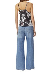 Canotta nera a fiori con spalline sottili, abbinata a jeans in denim blu chiaro a gamba larga con una texture sbiadita e tasche posteriori.