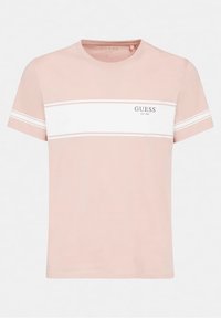 Camiseta de cuello redondo de color rosa claro, hecha de algodón, con una franja horizontal blanca en el pecho que lleva el logotipo de "GUESS" y el año de establecimiento.