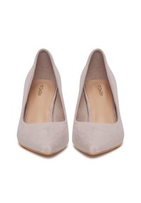 Par de zapatos de tacón altos de punta en ante beige con plantillas lisas de color marrón claro, vistos desde el frente sobre un fondo blanco.