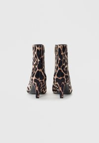Bottines à imprimé léopard avec une texture en velours doux, talons courts et fermeture éclair à l'arrière. Présente un design à bout pointu.