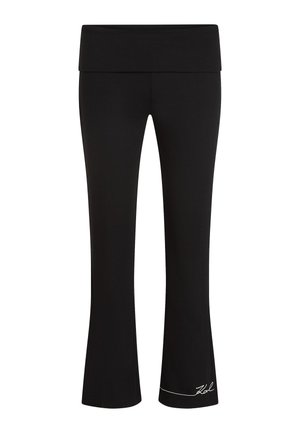 Črne zvončaste joga hlače z širokim pasom, rebrasto teksturo in belim logotipom blizu roba. Oblikovane za udobje in prilagodljivost.