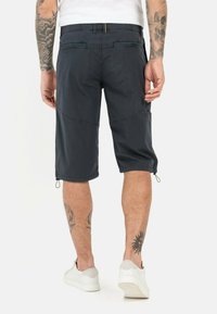 Dunkelgraue Shorts aus leichtem Stoff, mit entspannter Passform, seitlichen Taschen, verstellbaren Säumen und einer glatten Textur.