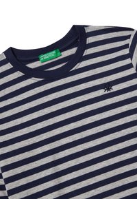 T-shirt a righe blu navy e grigio, realizzato in cotone. Presenta un collo tondo e un piccolo logo di polpo sul lato sinistro del petto. L'etichetta riporta "UNITED COLORS OF BENETTON."