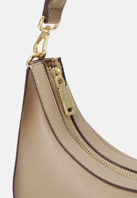 Beige leather handbag featuring dual zippers with gold hardware, smooth texture, and contrasting brown accents along edges.