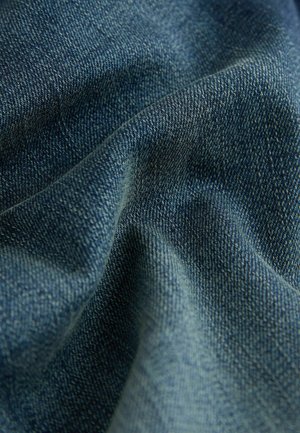 Donkerblauwe denimstof met een gestructureerde weving, met diepe indigo kleurvariaties en een zachte, gekreukelde uitstraling.