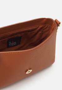 Brązowy portfel z sztucznej skóry o fakturowanej powierzchni, z zapięciem na złoty zatrzask oraz tkaninowym wnętrzem z metką marki.