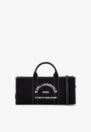 Melnas audekla soma ar baltu logo tekstu, divām augšējām rokturām un noņemamu pleca siksnu. Kontrastējošā šūšana piešķir vizuālu interesi.