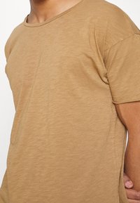 Krátké tričko s krátkými rukávy, vyrobené z lehké látky, s kulatým výstřihem a jemnou texturou s nenápadným melírovaným vzorem.