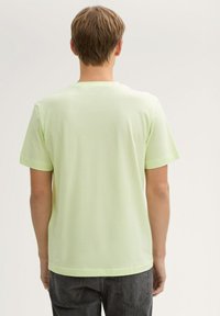 Lichtgroene T-shirt met korte mouwen, gemaakt van gladde stof, heeft een ronde halslijn, nette naden en een relaxed fit.