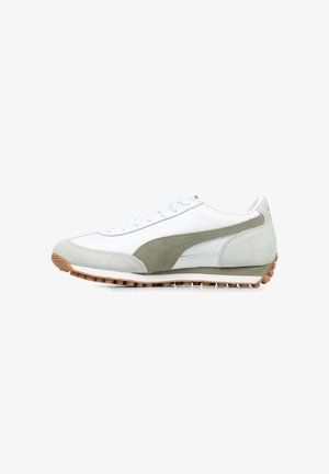 Chaussure de sport blanche avec des accents en suède vert clair, une semelle en caoutchouc et un design à lacets. Présente un panneau latéral texturé et des détails cousus.