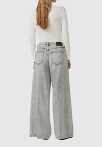 Jeans o szerokich nogawkach w jasnoszarym denimmie, z wysokim stanem, tylnymi kieszeniami i czarnym akcentem w pasie. Teksturowana tkanina z wyblakłym wykończeniem.