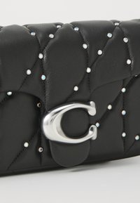 Black leather clutch bag with quilted texture, adorned with small iridescent studs, featuring a silver metal clasp.
