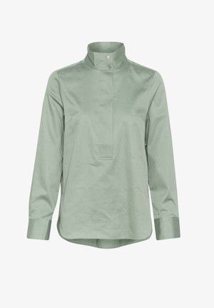 Gaiši zaļš krekls ar garām piedurknēm, augsta apkakle, priekšējā pogu aizdare un taisna griezuma. Gluda auduma ar smalku spīdumu un piegrieztām aprocēm.