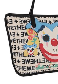 Geantă tote din pânză cu un design mare de față de clovn în roșu, albastru și galben, cu accente florale și modele de text negre. Margini și mânere negre.