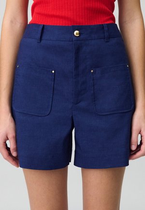 Pantaloni corti blu navy in lino, con due tasche frontali con patta arrotondata, chiusura con bottone dorato e vestibilità sartoriale.