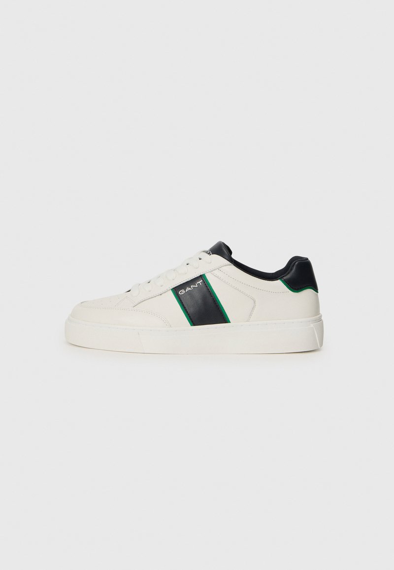 Weiße Sneakers mit einem Obermaterial aus texturiertem Leder, schwarzen Akzenten und einem grünen Streifen. Die Schuhe haben eine abgerundete Zehenpartie und eine flache Gummisohle.