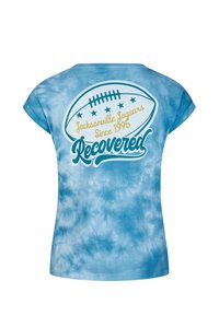 Ljust blå tie-dye t-shirt med en fotbollsgrafik, texten "Jacksonville Jaguars Sedan 1995" och "Återvunnen" i kontrasterande färger.