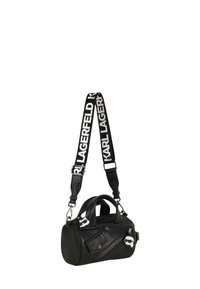 Bolso de cuero negro con forma redondeada, que cuenta con un cierre con cremallera, dos asas superiores y una correa ajustable con el logo de la marca.