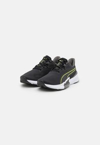 Scarpe sportive nere con tomaia in rete, dettagli verdi, punta rotonda e suola bianca, caratterizzate da una superficie texturizzata e design con lacci.