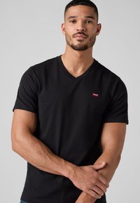 Fekete v-nyakú, rövid ujjú pamut póló, bal mellrészen kis piros Levi's logóval. Sima textúrájú.