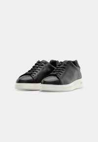 Schwarze Ledersneaker mit glatter Oberfläche, runder Zehenpartie, weißer Gummisohle und tonalen Schnürsenkeln. Verfügt über einen gepolsterten Kragen für zusätzlichen Komfort.