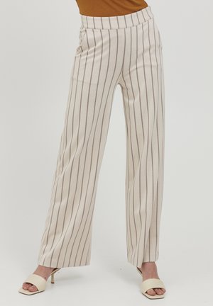 Cream wide-leg trousers with thin vertical brown stripes worn with beige open-toe heels on a plain background.